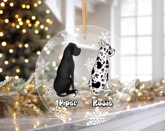 Peut inclure: Une boule de Noël ronde et transparente avec un motif de flocons de neige blancs. Deux grands danois noirs et blancs sont assis côte à côte. Les chiens s'appellent "Piper" et "Rosie".