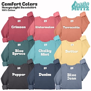 May include: A collection of Comfort Colors heavyweight sweatshirts in various colors, including crimson, watermelon, terracotta, blue spruce, chalky mint, butter, pepper, denim, and blue jean. Each sweatshirt is 100% cotton and features the brand name "Monster Muttz".