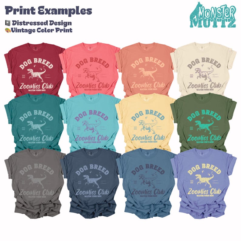 May include: A collection of various colored t-shirts with the text "DOG BREED" and "Zoomies Club" printed on the front. The shirts feature a distressed design and vintage color print, with a dinosaur graphic. The Monster Muttz logo is in the upper right corner.
