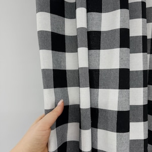 May include: A fabric curtain featuring a classic black and white buffalo check pattern. The textile displays a repeating grid of alternating solid black and white squares, creating a high-contrast geometric design across the entire surface.