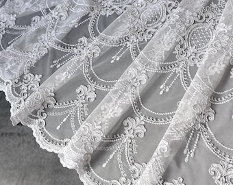 May include: A sheer white tulle fabric featuring intricate white embroidery in a repeating damask-inspired pattern. The design includes scalloped edges, delicate floral motifs, and fine threadwork detailing across the semi-transparent surface.