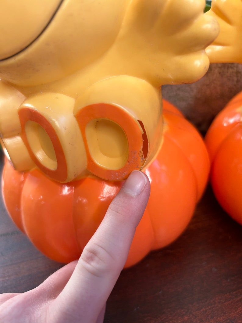 May include: Two orange plastic pumpkins with yellow bird figures on top. The bird on the left has the word "DO" on its chest.