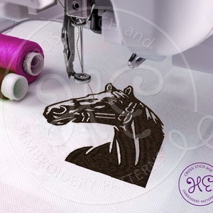 Pu&ograve; includere: Un disegno di ricamo di testa di cavallo marrone che viene cucito su un tessuto bianco da una macchina da cucire. Il disegno &egrave; delineato con filo nero e la testa del cavallo &egrave; rivolta verso il lato sinistro dell'immagine. La macchina da cucire si trova nell'angolo in alto a sinistra dell'immagine. Due bobine di filo sono visibili nell'angolo in alto a sinistra dell'immagine.