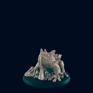 May include: A gray, detailed miniature of a fantasy creature resembling a toad with a long tongue, sitting on a green base.