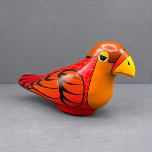 Könnte beinhalten: Eine handbemalte Vogelfigur aus Holz mit leuchtend orangefarbener Brust und Kopf, einem gelben Schnabel mit schwarzem Tränendetail und roten Flügeln, die mit komplizierten schwarzen Linienmustern verziert sind. Der Vogel hat eine glatte, glänzende Oberfläche.