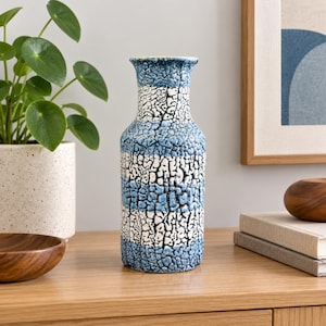 May include: A cylindrical ceramic vase featuring a textured crackle glaze finish with alternating horizontal bands of blue and white. The vase has a narrow neck that flares slightly at the top rim, showcasing a distinct, rugged surface pattern.