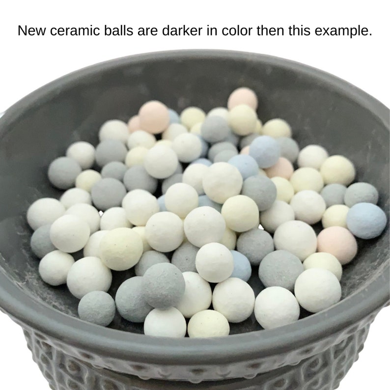 May include: A gray ceramic bowl filled with small, round ceramic balls in various pastel colors, including white, gray, blue, and yellow. The text at the top says, "New ceramic balls are darker in color then this example."