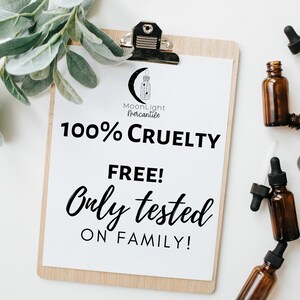 May include: A white sheet of paper with black text on a wooden clipboard. The text reads "MoonLight Mercantile 100% Cruelty Free! Only tested on family!"  The clipboard is surrounded by small brown glass bottles with droppers.