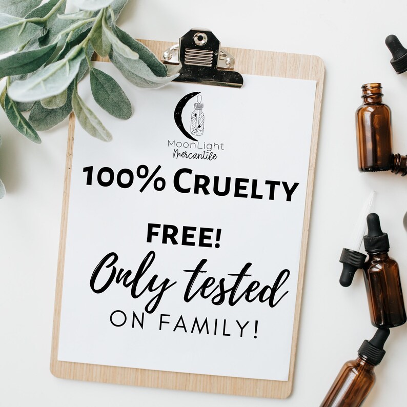 May include: A white sheet of paper with black text on a wooden clipboard. The text reads "MoonLight Mercantile 100% Cruelty Free! Only tested on family!"  The clipboard is surrounded by small brown glass bottles with droppers.