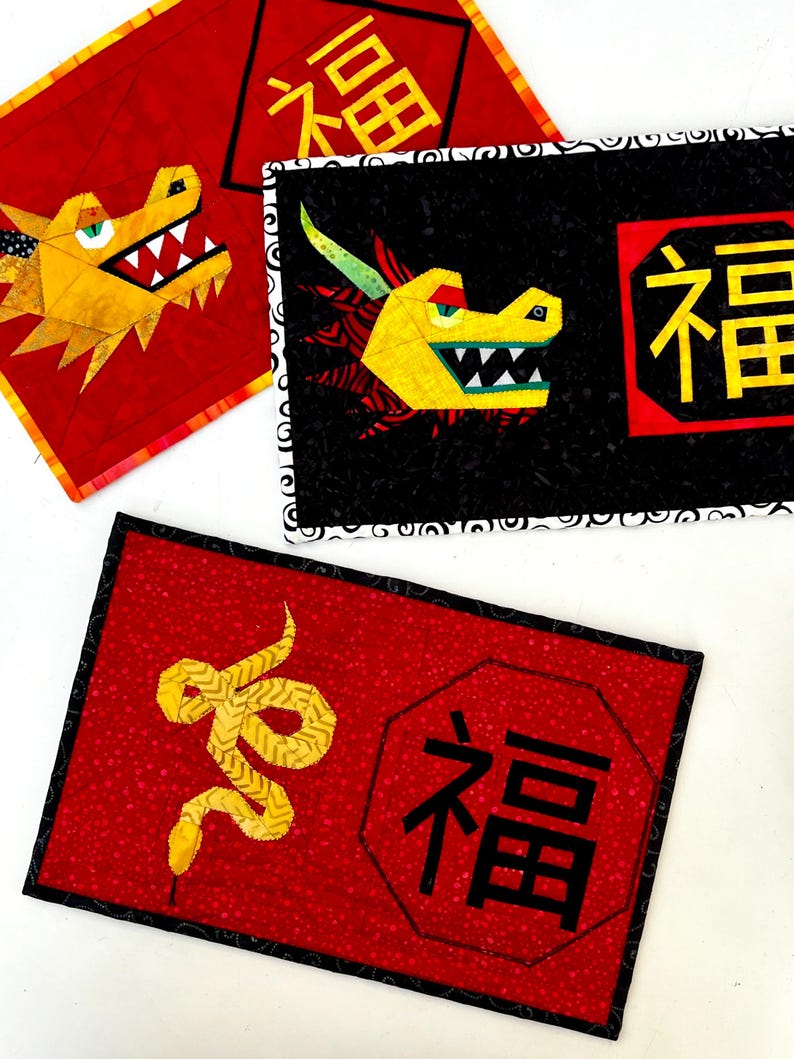 May include: Three red fabric squares with black borders and Chinese characters. The squares feature a yellow dragon, a yellow snake, and the character "福" (Fu) meaning "good fortune".