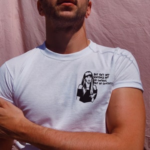 Könnte beinhalten: Weißes T-Shirt mit einer Schwarz-Weiß-Illustration einer Frau und dem Text "But isn't any sentence out of context, out of context?" auf der Vorderseite. Das T-Shirt hat einen Rundhalsausschnitt und kurze Ärmel.