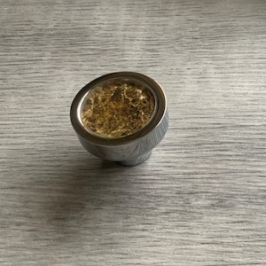 May include: A round, silver cabinet knob with a brown, marbled centre.