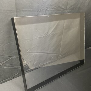 May include: A black framed picture frame with a clear glass insert. The frame is made of a thin, black metal and has a simple, modern design.
