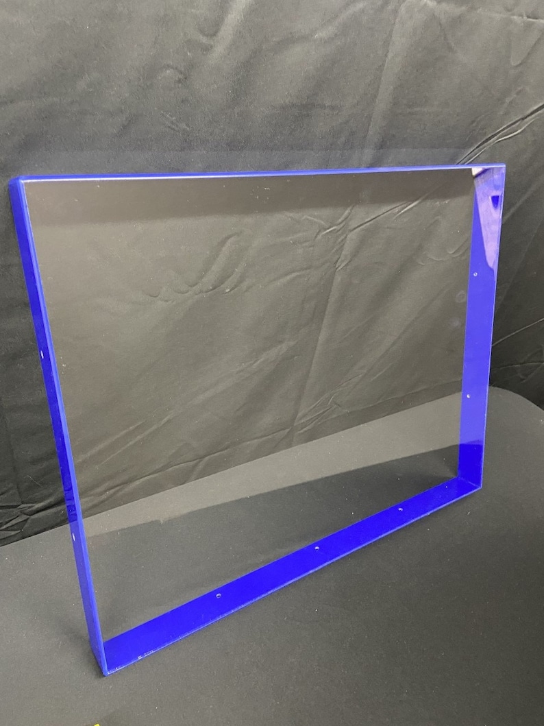 May include: A clear acrylic frame with a blue border. The frame is rectangular and has several small holes along the edges.