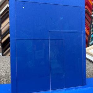 May include: Three clear acrylic sheets of different sizes, stacked on top of each other, on a blue surface.