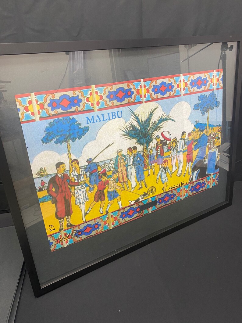 May include: A framed illustration of a beach scene with people in colorful clothing. The illustration is titled "MALIBU" and features a palm tree, a dog, and a beach umbrella. The illustration is framed in a black frame.