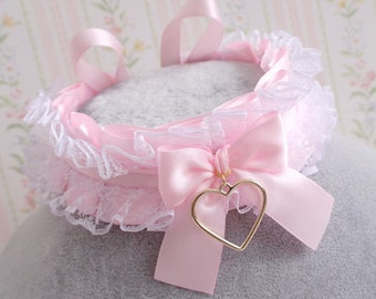 May include: A pink satin choker with a white lace trim and a pink satin bow with a gold heart charm.
