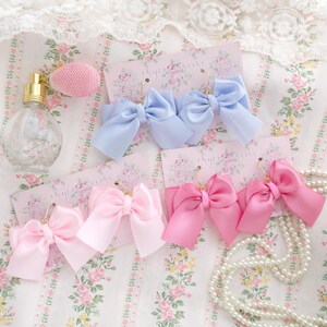 May include: Three pairs of bow earrings on white card stock with the text "myecocraft" printed on each card. The bows are made of satin ribbon in light blue, pink, and hot pink.