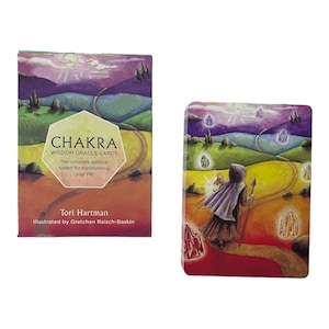 Könnte beinhalten: Ein Deck Chakra Wisdom Oracle Cards mit einer farbenfrohen Illustration einer Person, die auf einem Weg mit Kristallen geht. Der Text auf der Schachtel lautet "CHAKRA WISDOM ORACLE CARDS The complete spiritual toolkit for transforming your life Tori Hartman Illustrated by Gretchen Raisch-Baskin"