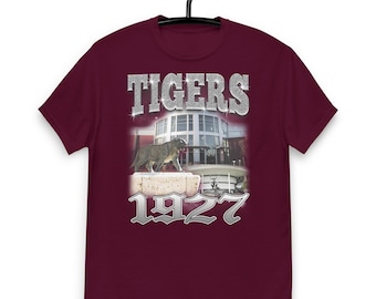 May include: A maroon t-shirt with a silver graphic print of a tiger, a building, and the text "TIGERS 1927".