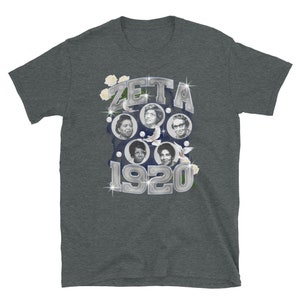 May include: A dark heather grey t-shirt with a silver graphic of the word "ZETA" and the year "1920" surrounded by white flowers and doves. The graphic features four women's faces in circular frames.