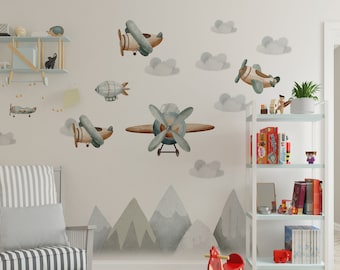 May include: A light gray rocking chair with a striped cushion and a gray and white pillow. A wooden rocking horse with a red saddle is in the foreground. The wall behind the chair is decorated with a whimsical scene of airplanes, clouds, and mountains.