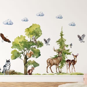 May include: A set of watercolor wall decals featuring a forest scene with a large deciduous tree, a pine tree, and various animals including a wolf, deer, raccoon, squirrel, fox, owls, and an eagle, accented by several light blue clouds.