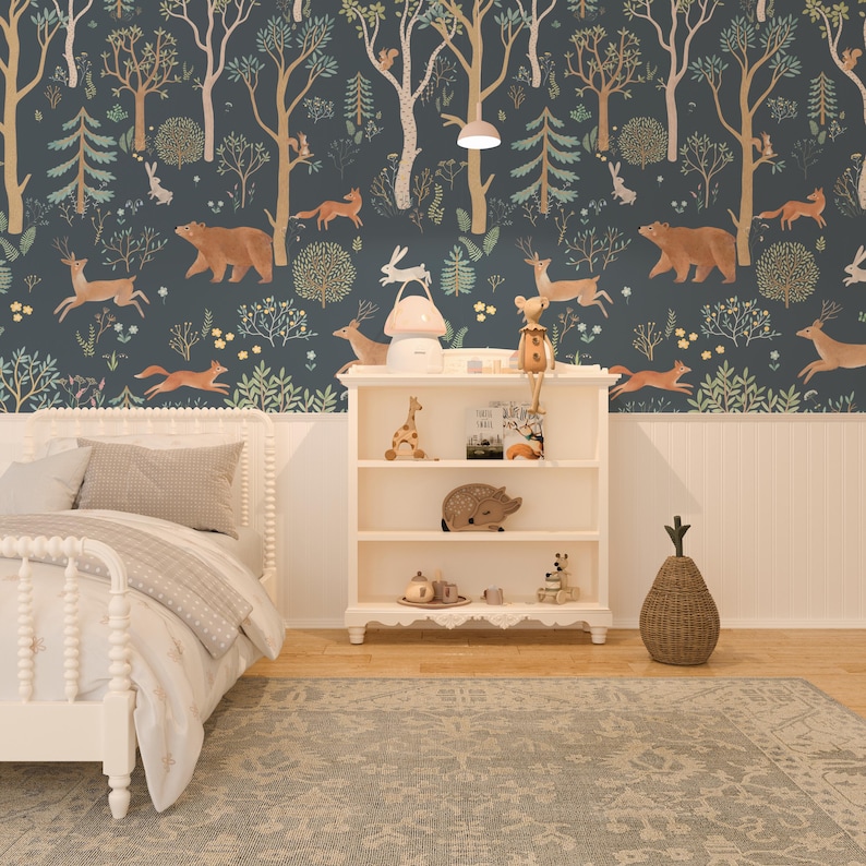 May include: A white wooden bed frame with a white headboard and footboard. The bed is made with a white duvet cover and a beige throw blanket. The bed is in a room with a dark blue wallpaper featuring a woodland scene with animals, trees, and flowers. A white bookshelf with three shelves is to the right of the bed. The bookshelf is decorated with a giraffe figurine, a small pig figurine, a teacup and saucer, and a stack of books. A wicker pineapple-shaped basket is on the floor next to the bookshelf.