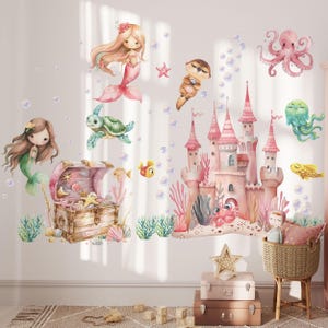 May include: A set of underwater-themed wall decals featuring a pink castle, a wooden treasure chest, two mermaids, an octopus, a sea turtle, a jellyfish, an otter, and various fish, starfish, and bubbles in soft pastel colors on a white wall.