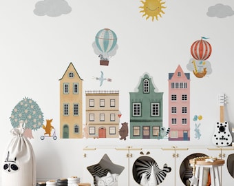 May include: A set of wall decals featuring a row of colorful buildings, a yellow sun, grey clouds, and various animals including a fox on a scooter, a bear, and a giraffe in a hot air balloon. The scene includes a zebra in a balloon and a bird.