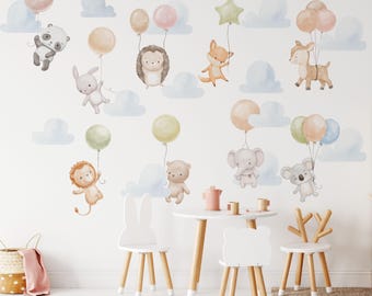 May include: A set of wall decals featuring watercolor illustrations of a panda, rabbit, hedgehog, fox, deer, lion, bear, elephant, and koala, each holding colorful balloons, accompanied by light blue clouds on a white wall.