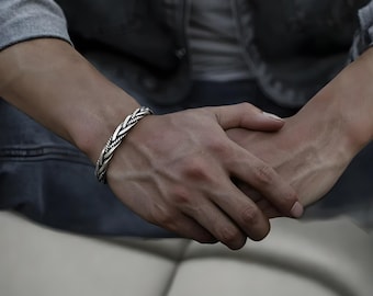 Può includere: Un braccialetto rigido in argento intrecciato con un design attorcigliato.