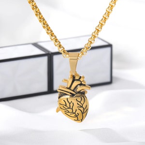 Pu&ograve; includere: Una collana con catena dorata con un ciondolo a forma di cuore anatomico dettagliato.
