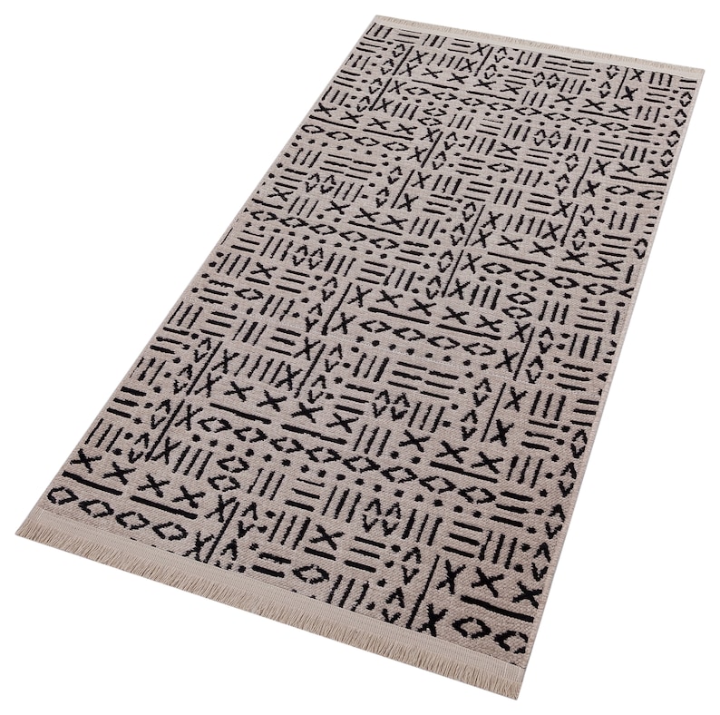 May include: A beige and black patterned rug with a fringe border. The pattern is geometric and abstract, featuring lines, dots, and crosses.