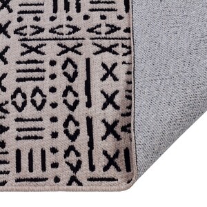 May include: A beige rug with a black geometric pattern. The rug has a gray backing.