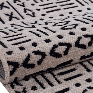 May include: Close-up of a beige and black patterned rug with a geometric design. The rug has a fringe border.