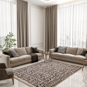 May include: A living room with two beige sofas, a patterned rug, and a small table with two glasses. The room has large windows with sheer curtains and beige drapes.