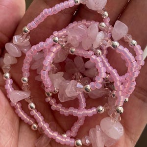 Puede incluir: Un brazalete de cuentas rosadas con chips de cuarzo rosa y cuentas plateadas. El brazalete est&aacute; en capas y tiene un aspecto delicado y femenino.