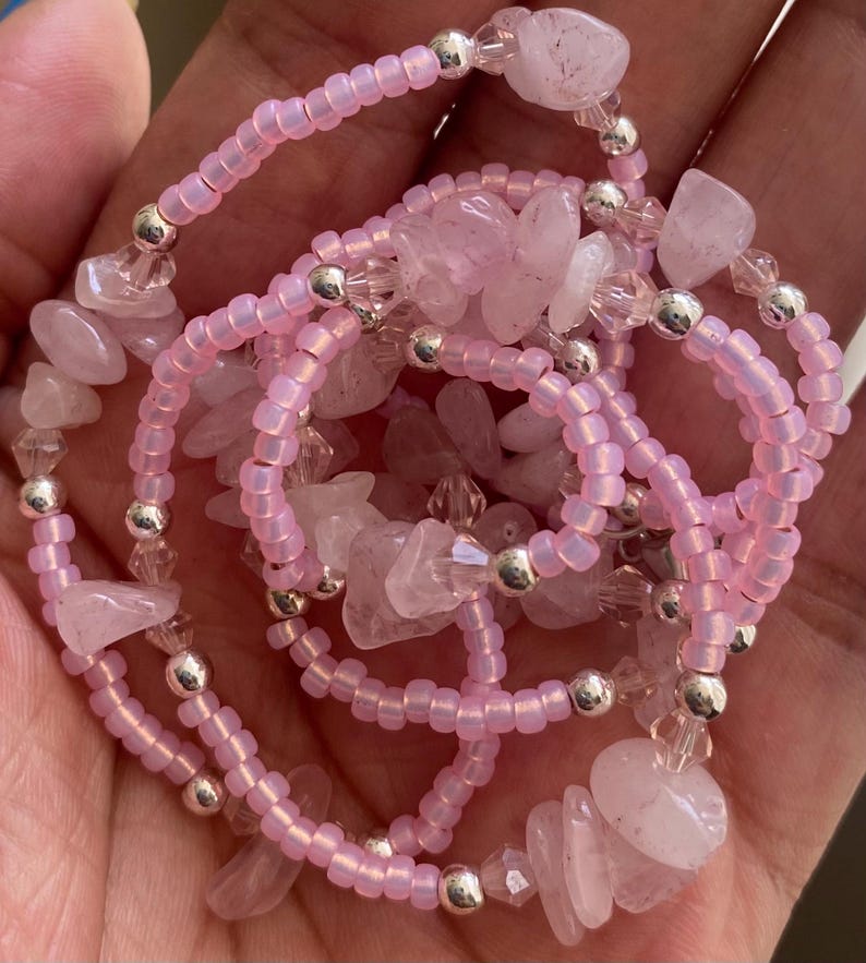Puede incluir: Un brazalete de cuentas rosadas con chips de cuarzo rosa y cuentas plateadas. El brazalete est&aacute; en capas y tiene un aspecto delicado y femenino.