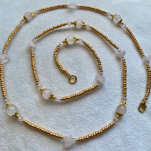 May include: A gold beaded necklace with pink and clear crystal beads and a matching bracelet. The necklace has a lobster clasp closure.