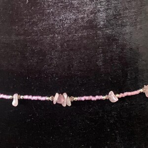 Puede incluir: Una cadena de cintura de cuentas rosadas y plateadas con detalles de piedras rosadas.