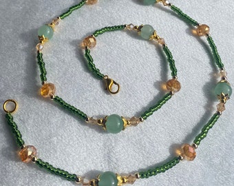 Op de afbeelding: Een groene en gouden kralenketting met een sluiting. De ketting heeft afwisselend groene en gouden kralen, met grotere groene kralen die over de hele lengte zijn verdeeld.
