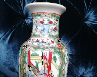 Op de afbeelding: Een witte porseleinen vaas met een rood, groen en blauw bloemenontwerp en een scène met mensen in traditionele Chinese kleding. De vaas heeft een brede opening en een smalle basis.