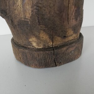 May include: A wooden sculpture of a hand with a rough, rustic texture. The hand is brown and has a natural wood finish. The sculpture is made from a single piece of wood and has a unique, organic shape.