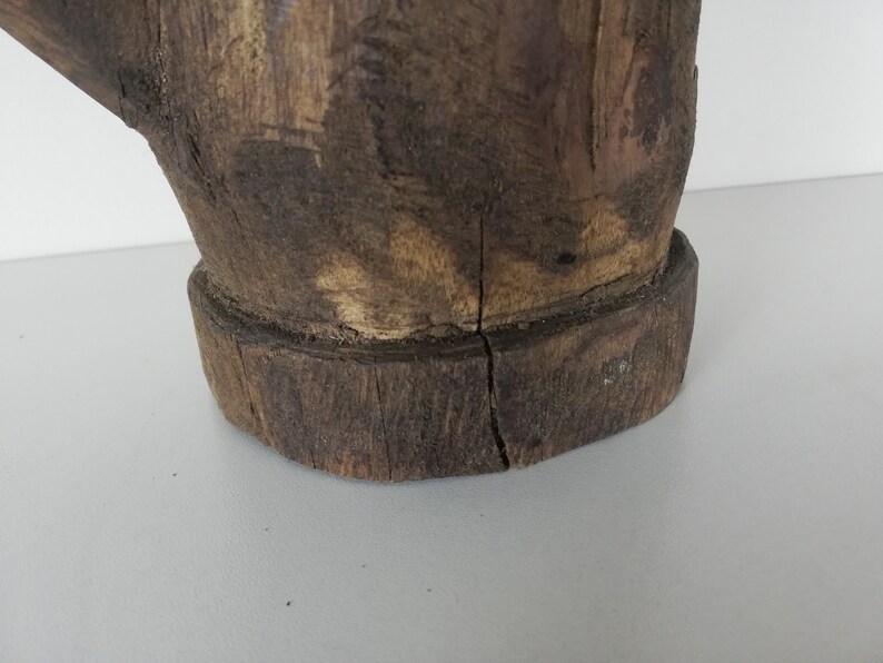 May include: A wooden sculpture of a hand with a rough, rustic texture. The hand is brown and has a natural wood finish. The sculpture is made from a single piece of wood and has a unique, organic shape.