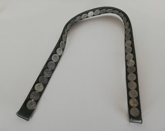 May include: A dark green belt adorned with silver-colored coins. The belt has a rectangular buckle and a series of coins attached along its length. The coins are evenly spaced and add a decorative element to the belt.