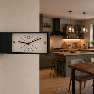 Peut inclure: Une horloge murale rectangulaire avec un cadre noir et un cadran blanc. L'horloge présente des aiguilles noires pour les heures et les minutes, avec les chiffres 3, 6, 9 et 12 imprimés en noir. Les autres repères sont des lignes noires.