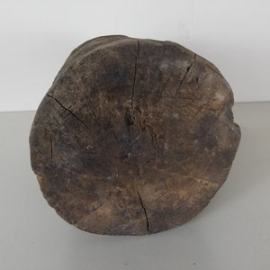 May include: A round, dark brown wooden stump with a rough, textured surface. The stump is a natural wood product and has a circular shape.