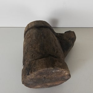 May include: A rustic wooden mortar and pestle, carved from a single piece of wood. The mortar is a deep brown color and has a rough, textured surface. The pestle is slightly lighter in color and has a smooth, rounded head.