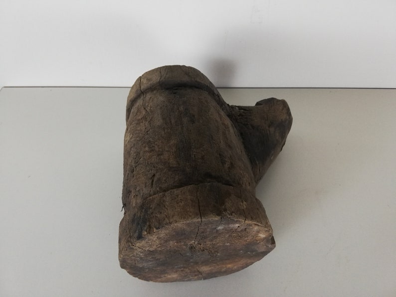 May include: A rustic wooden mortar and pestle, carved from a single piece of wood. The mortar is a deep brown color and has a rough, textured surface. The pestle is slightly lighter in color and has a smooth, rounded head.